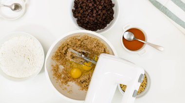 Çikolatalı kurabiye tarifi. Bir kasede tereyağı, şeker ve yumurta karışımı, beyaz arkaplanı kapatın, yukarıdan görünüm