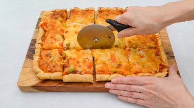 Pizza kesicisi kullanan bir kadın. Tahtaya yakın Mozzarella peynirli vejetaryen pizza.