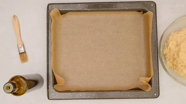 Baking pan covered with parchment paper, close up baking process, flat lay