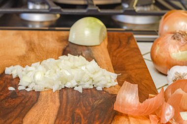 Doğranmış beyaz soğan mutfak tezgahının tahta kesme tahtasına yakın.