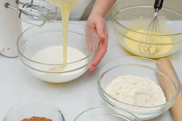 Close up baking process. Chef adds condensed milk into a bowl with whisked egg whites. Step by step chocolate cake recipe