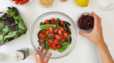 Taze kiraz domatesli marul salatası, kuru kızılcık, fındık ve ballı hardal salatası sosu tarifi. Yukarıdan yaklaş, kadın elleri