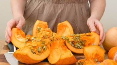 Kadın, tahta kesme tahtasıyla portakal kabağını dilimlere ayırıyor. Adım adım kabak püresi tarifi, yaşam tarzı