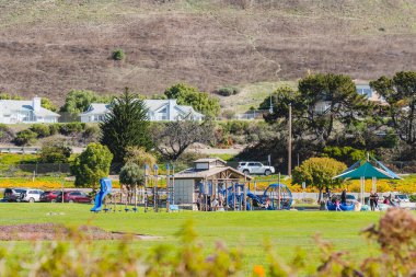 Pismo Beach, California, ABD - 1 Mart 2021 Dinozor Mağara Parkı, oyun alanı ve yürüyüş yolu, çimenli çimler, yeşil tepeler ve okyanus manzarası. Park, şehrin en çok kullanılan tesisidir..