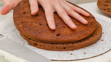 Çikolatalı pasta üç katmana bölündü. Adım adım çikolatalı pasta, çikolatalı krema tarifi, kadın eli, beyaz mutfak masası arka planı