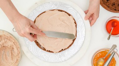 Pastayı monte ediyorum. Kadın elleri pastanın bir kısmını çikolatalı kremayla kaplıyor. Adım adım çikolatalı kek tarifi, pişirme işlemini kapat
