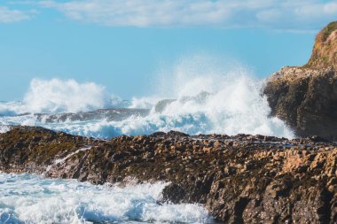 Kayalık kayalıklar ve arka planda bulutlu güzel gökyüzü olan fırtınalı Pasifik okyanusu. Los Osos, Kaliforniya kıyı şeridi