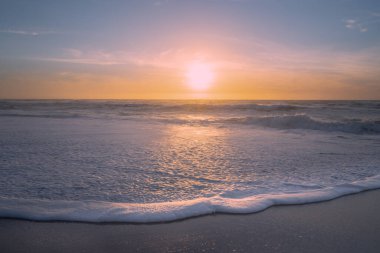 Yumuşak mavi ve sarı renkli deniz manzarası gibi soyut bir rüya. Okyanus, kumlu sahil ve gün batımında bulutlu gökyüzü.
