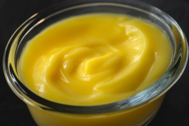 Cam bir kasede limonlu puding. Arka planda koyu renk.