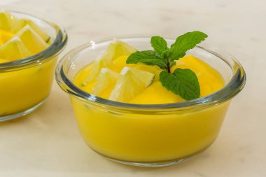 Dilimlenmiş limon ve nane yaprağıyla servis edilen cam kâseler açık mermer arka planda.