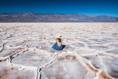 Salt Flats in Death Valley National Park. Silhouette of woman enjoying view. Badwater Basin hiking trail, trail adventure through upheaved salt plates below sea level. clipart