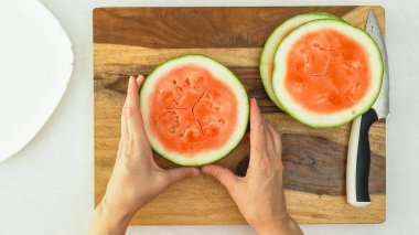 Tahta kesme tahtasında karpuz dilimleri, düz yatış, kadın eli.