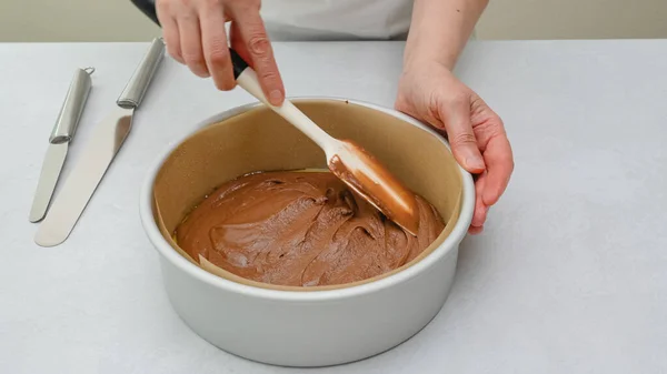 Cake pan with cake batter close up on kitchen table, close up baking process. Chocolate cake step by step recipe, woman hands
