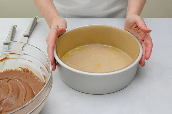 Pasta tepsisi parşömen kağıdıyla mutfak masasının üzerine konmuş. Çikolatalı pasta adım adım, pişirme işlemini kapat