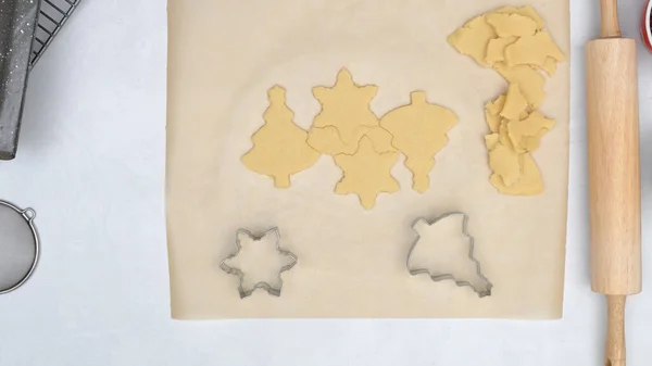 Christmas shortbread cookies with raspberry jam recipe. Chef using cookie cutters to stamp Christmas cookies, pine tree cutter and star cutter