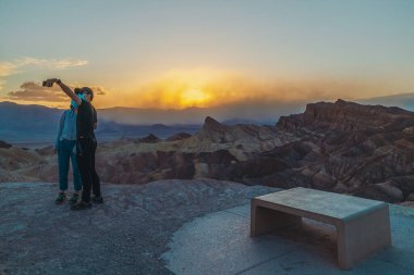 Ölüm Vadisi, Kaliforniya, ABD... 14 Nisan 2021 Zabriskie Point Sunset, Ölüm Vadisi Ulusal Parkı 'nda gün batımını görmek için en popüler yerlerden biri. Vadiye bakan turistler.