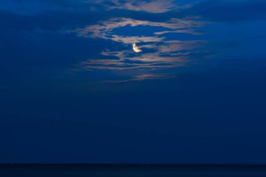 Hilal ay gece sakin okyanusun üzerinde yansıyor.