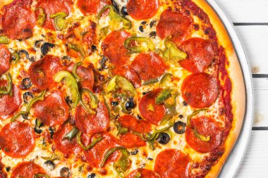 Yeşil dolmalık biberli ve metal tepside siyah zeytinli pepperoni pizza manzarası.