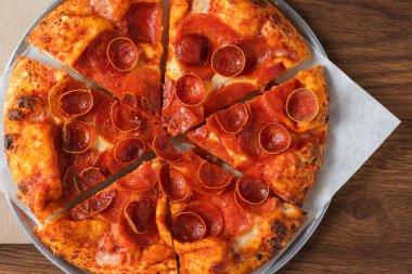 Altın hamurlu ve gümüş tepside erimiş peynirli dilimlenmiş pepperoni pizza..