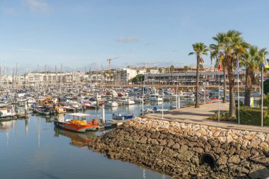 Lagos, Portekiz, 8 Kasım 2025. Düzinelerce tekne, sallanan bayraklar ve palmiyelerle çerçevelenmiş gezinti alanı yakınlarındaki marinayı dolduruyor..