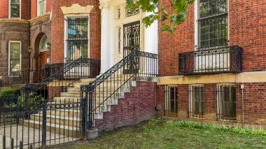 İşlenmiş demir parmaklıkları ve detaylı mimari özellikleri olan zarif kırmızı tuğlalı binalar sakin bir sokak hattını oluşturur..