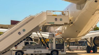 Lizbon, Portekiz, 20 Mayıs 2025. Mobil elektrikli merdivenler bir EasyJet uçağının ön kapısına yerleştirilirken yer servis araçları yakınlarda çalışır..