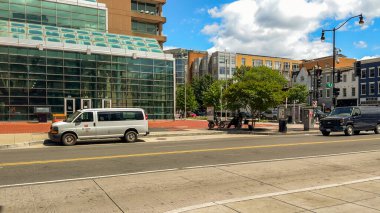 Washington D.C., ABD, 24 Mayıs 2025. U Caddesi ile 14. caddenin köşesindeki modern cam binanın yanına beyaz bir minibüs park edilmiş..