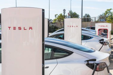 Loule, Portekiz, 22 Kasım 2025. Birkaç Tesla elektrikli aracı tam şarj istasyonunda şarj olurken yan yana park edilir..