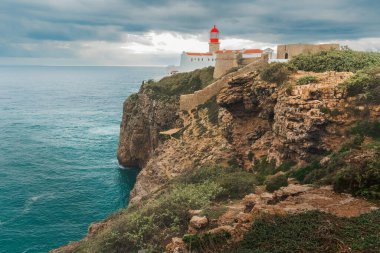 Tarihsel deniz feneri kompleksi dik bir kayalıktaki dalgaların üzerinde cesurca durur..