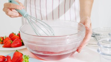 Mutfak tezgahında cam bir kasede el çırpma çileği karışımı..