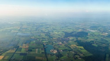 Yeşil tarlalar ve küçük kasabalardan oluşan bir mozaik tüm araziye yayılır..