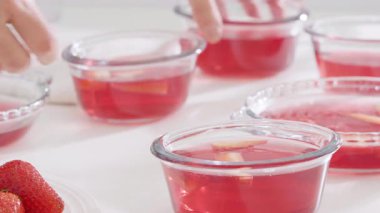 Ayarlamak için bir kaseye çilekli jelatin karışımı döküyorum. Yüksek kalite 4k görüntü