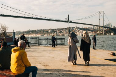 İstanbul, Türkiye, 7 Ocak 2025. Köprünün altındaki rıhtım boyunca yürüyen yayalar şehrin karşı kıyılarına yayılmış durumdalar..