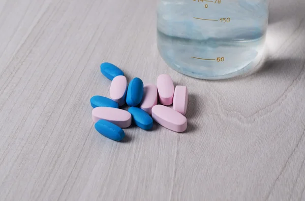 Blaue und rosa probiotische Pillen oder Vitamine auf einem hölzernen Hintergrund. Thema Pharmakologie — Stockfoto