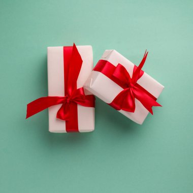 Aqua mavisi arka planda parlak kırmızı fiyonklarla bağlanmış iki beyaz hediye kutusu ve metin için boşluk. Noel ve Yeni Yıl afişleri için iyi.