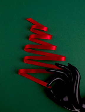 İpek kırmızı kurdele ve parlak yeşil zemin üzerinde plastik manken elinden yapılmış Noel ağacı. Mutlu Noeller ve Mutlu Yeni Yıl arkaplanı ve mesaj için boş alan.