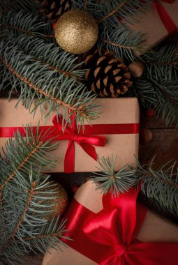 Noel süslemeleri arasında kırmızı ipek fiyonklu hediye kutusu tahta bir masada. Mutlu Noeller ve mutlu yıllar..