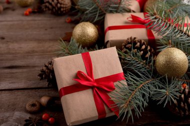 Noel süslemeleri arasında kırmızı ipek fiyonklu hediye kutusunu ahşap bir masada kapat. Mutlu Noeller ve mutlu yıllar..