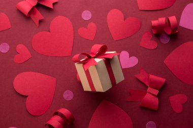 Kağıt sanatı Sevgililer Günü pankartı, el yapımı hediye kutusu, kağıt kesiği kurdele, fiyonk ve kırmızı arka planda mesaj için yeri olan bir sürü kalp..