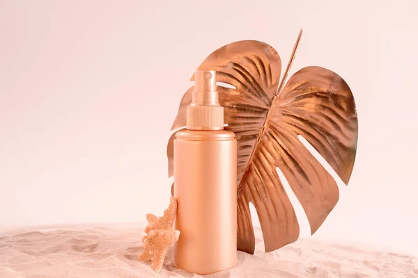 Crema protector solar o botella de loción con hoja de monstera tropical coloreada en oro rosa. Asistencia sanitaria durante el concepto de vacaciones. — Foto de Stock