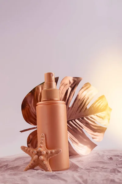 Crema protector solar o botella de loción con hoja de monstera tropical coloreada en oro rosa. Cuidado de la salud durante el concepto de vacaciones. — Foto de Stock