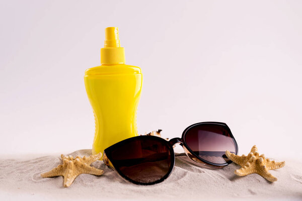 Sunscreen spray bottle and summer straw hat beach shoes and sunglasses against white copy space. Summer vacation banner concept.