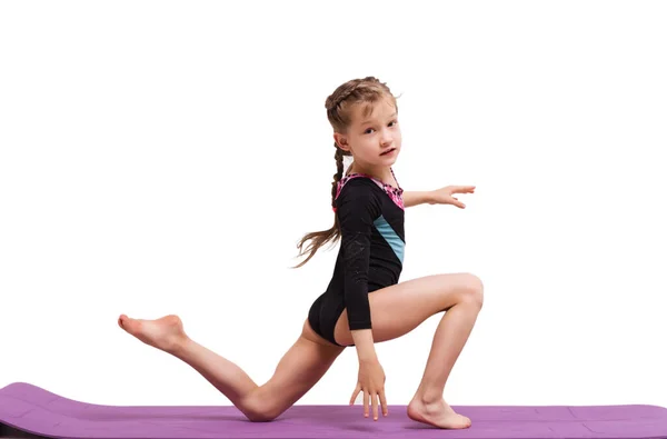 Linda niña haciendo ejercicios gimnásticos contra el blanco. — Foto de Stock