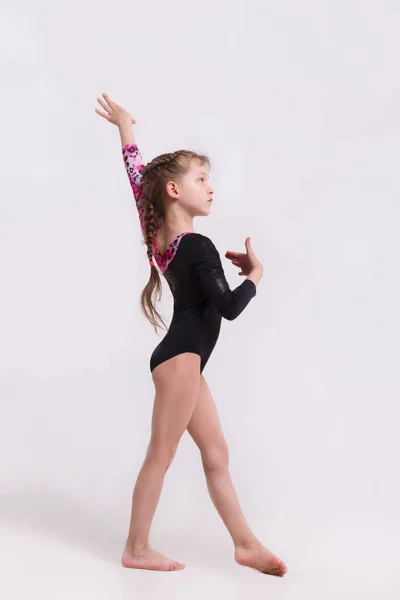 Linda niña haciendo ejercicios gimnásticos contra el blanco. — Foto de Stock