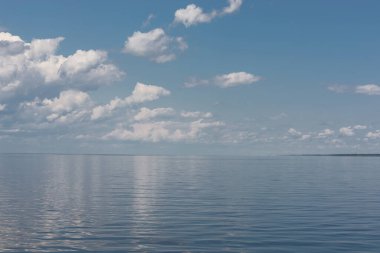Minimalist deniz manzarası ve su yüzeyine yansıyan kabarık bulutlarla dolu güzel mavi bir gökyüzü..