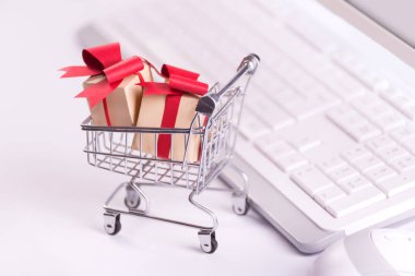 Çevrimiçi alışveriş ve e-ticaret konsepti fotoğrafı ve klavyeye karşı kağıt kesilmiş hediye kutularıyla dolu bir alışveriş arabası..