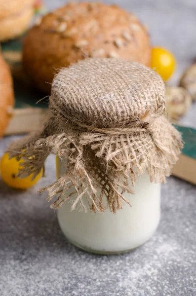 Iogurte caseiro em um pequeno frasco coberto por têxteis de artilharia. Ingrediente de café da manhã saudável. — Fotografia de Stock