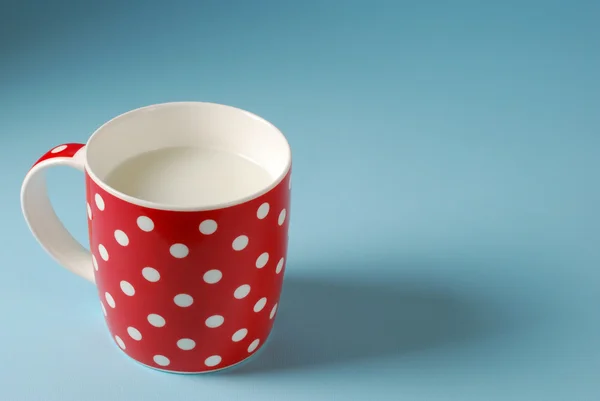 Tazza rossa di latte su sfondo blu — Foto Stock