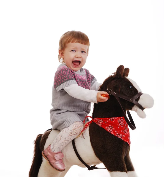 Petite fille sur son premier cheval jouet isolé sur un blanc — Photo