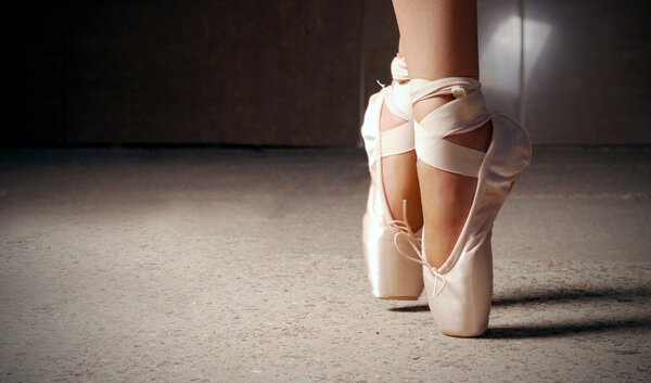 Feet of ballerina dancing in ballet shoes